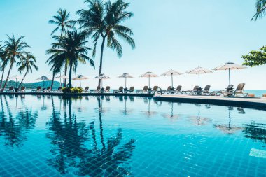 Güzel tropikal plaj ve deniz şemsiyesi ve sandalyesi otel tatil ve tatil için yüzme havuzunda.