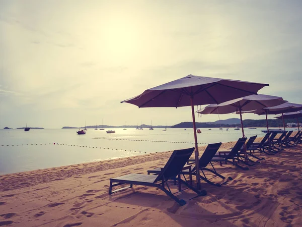 Şemsiye ve tropikal plaj deniz ve okyanus gündoğumu zaman seyahat ve tatil için sandalye