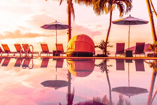Şemsiye ve lüks otel ve gündoğumu zaman seyahat ve tatil için Resort'ta yüzme havuzu etrafında sandalye ile güzel açık görünüm