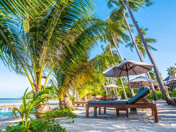 Şemsiye ve sandalyenin üstüne Hindistan cevizi hurma ağacının seyahat ve tatil etrafında mavi gökyüzü ile plaj ve okyanus