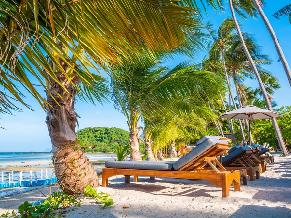 Şemsiye ve sandalyenin üstüne Hindistan cevizi hurma ağacının seyahat ve tatil etrafında mavi gökyüzü ile plaj ve okyanus