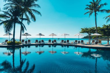 Güzel tropikal plaj ve deniz şemsiyesi ve sandalyesi otel tatil ve tatil için yüzme havuzunda.