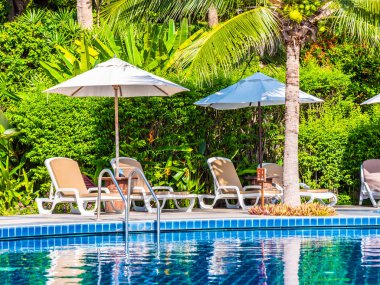 Şemsiye ve sandalye etrafında lüks otel ve resort tatil ve seyahat için açık yüzme havuzu