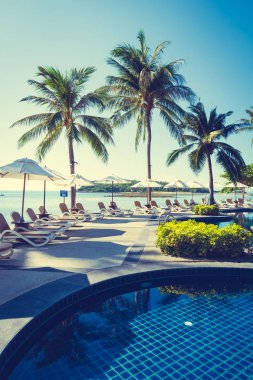 Güzel tropikal plaj ve deniz şemsiyesi ve sandalyesi otel tatil ve tatil için yüzme havuzunda.