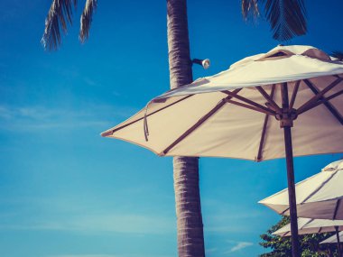 Hindistan cevizi hurma ağacı ile deniz okyanus seyahat ve tatil için mavi gökyüzü arka plan üzerinde Beyaz şemsiye