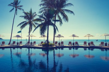 Güzel tropikal plaj ve deniz şemsiyesi ve sandalyesi otel tatil ve tatil için yüzme havuzunda.