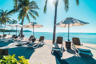 Güzel tropikal plaj ve deniz şemsiyesi ve sandalyesi otel tatil ve tatil için yüzme havuzunda.