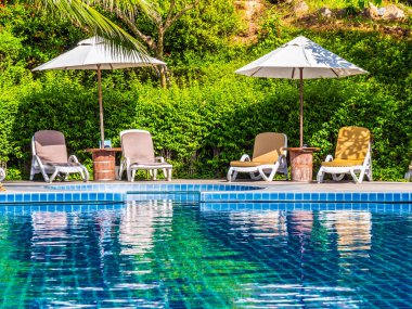 Şemsiye ve sandalye etrafında lüks otel ve resort tatil ve seyahat için açık yüzme havuzu