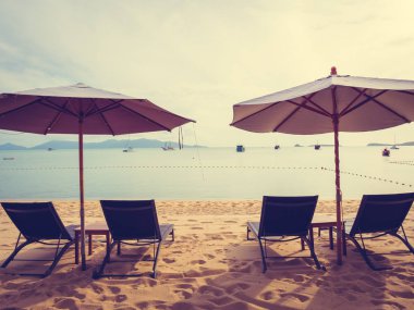 Şemsiye ve tropikal plaj deniz ve okyanus gündoğumu zaman seyahat ve tatil için sandalye