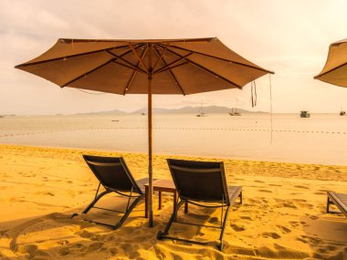 Şemsiye ve tropikal plaj deniz ve okyanus gündoğumu zaman seyahat ve tatil için sandalye