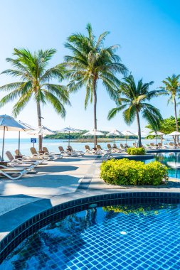 Güzel tropikal plaj ve deniz şemsiyesi ve sandalyesi otel tatil ve tatil için yüzme havuzunda.