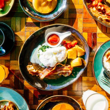 Sağlıklı kahvaltı seti yumurta pastırma ile portakal suyu süt ekmek kahve ve diğer ahşap masada krep