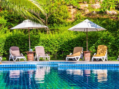 Şemsiye ve sandalye etrafında lüks otel ve resort tatil ve seyahat için açık yüzme havuzu
