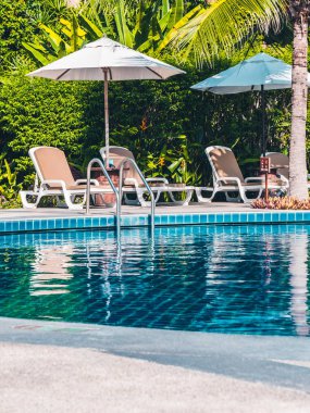 Şemsiye ve sandalye etrafında lüks otel ve resort tatil ve seyahat için açık yüzme havuzu