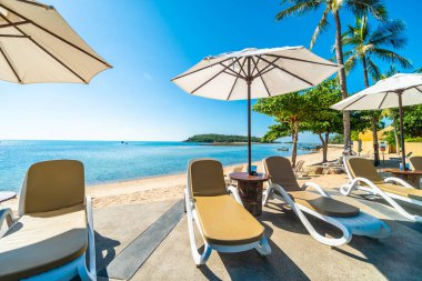 Güzel tropikal plaj ve deniz şemsiyesi ve sandalyesi otel tatil ve tatil için yüzme havuzunda.