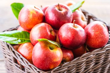 Bir sürü tablo üzerinde kahverengi sepet içinde kırmızı elma meyve