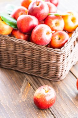 Bir sürü tablo üzerinde kahverengi sepet içinde kırmızı elma meyve