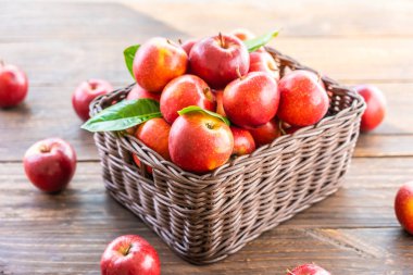 Bir sürü tablo üzerinde kahverengi sepet içinde kırmızı elma meyve