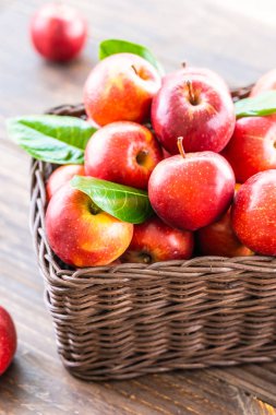 Bir sürü tablo üzerinde kahverengi sepet içinde kırmızı elma meyve