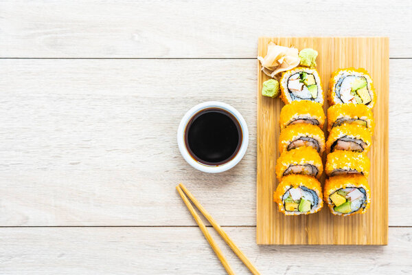 California maki rolls sushi on wooden plate with sauce and chopsticks - Japanese food style