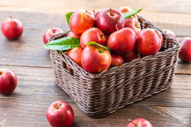 Bir sürü tablo üzerinde kahverengi sepet içinde kırmızı elma meyve