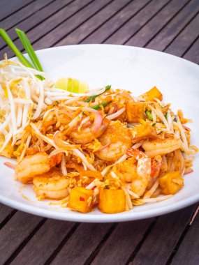 Ahşap masa üzerinde beyaz tabak karides ile Pad Tay erişte