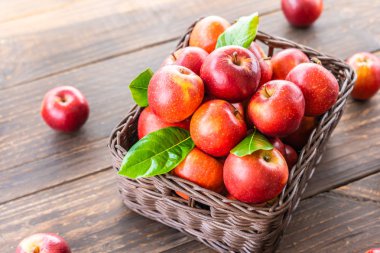 Bir sürü tablo üzerinde kahverengi sepet içinde kırmızı elma meyve