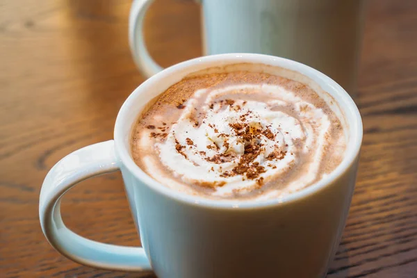 Hot cocoa and chocolate in white cup or mug on wooden table