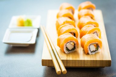 Somon Balık et suşi roll maki wasabi ve soya sosu - Japon yemekleri tarzı ahşap plaka üzerinde