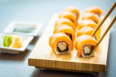 Somon Balık et suşi roll maki wasabi ve soya sosu - Japon yemekleri tarzı ahşap plaka üzerinde