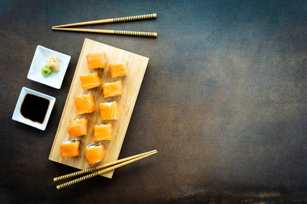 Somon Balık et suşi roll maki wasabi ve soya sosu - Japon yemekleri tarzı ahşap plaka üzerinde