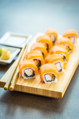 Somon Balık et suşi roll maki wasabi ve soya sosu - Japon yemekleri tarzı ahşap plaka üzerinde