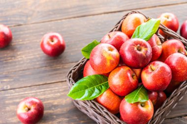 Bir sürü tablo üzerinde kahverengi sepet içinde kırmızı elma meyve
