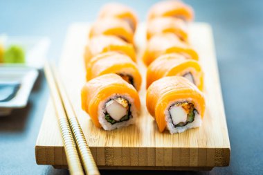 Somon Balık et suşi roll maki wasabi ve soya sosu - Japon yemekleri tarzı ahşap plaka üzerinde
