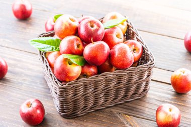 Bir sürü tablo üzerinde kahverengi sepet içinde kırmızı elma meyve