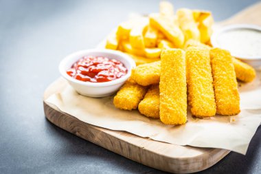 Balık parmak ve patates kızartması veya ahşap kesme tahtası - sağlıksız yiyecek stil üzerinde domates ketçap ve mayonez soslu cips