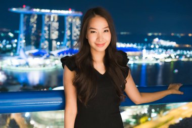 Güzel Asyalı kadınlar gülümseme ve mutlu gece Singapur şehir manzaralı