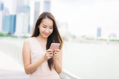 Güzel Asyalı kadın konuşmak veya metin için akıllı telefon veya cep telefonu kullanarak