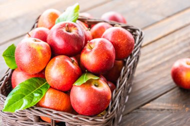 Bir sürü tablo üzerinde kahverengi sepet içinde kırmızı elma meyve