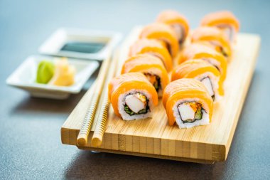 Somon Balık et suşi roll maki wasabi ve soya sosu - Japon yemekleri tarzı ahşap plaka üzerinde