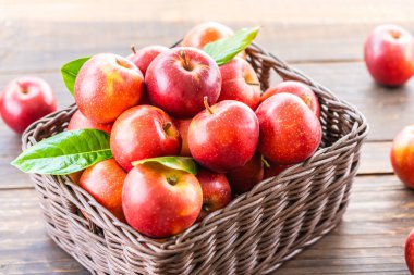 Bir sürü tablo üzerinde kahverengi sepet içinde kırmızı elma meyve