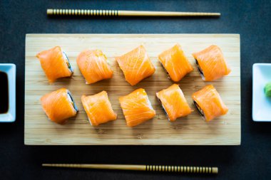 Somon Balık et suşi roll maki wasabi ve soya sosu - Japon yemekleri tarzı ahşap plaka üzerinde