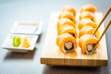 Somon Balık et suşi roll maki wasabi ve soya sosu - Japon yemekleri tarzı ahşap plaka üzerinde