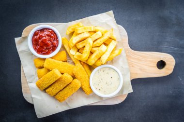 Balık parmak ve patates kızartması veya ahşap kesme tahtası - sağlıksız yiyecek stil üzerinde domates ketçap ve mayonez soslu cips