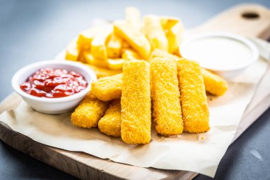 Balık parmak ve patates kızartması veya ahşap kesme tahtası - sağlıksız yiyecek stil üzerinde domates ketçap ve mayonez soslu cips