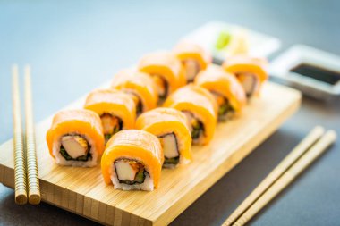 Somon Balık et suşi roll maki wasabi ve soya sosu - Japon yemekleri tarzı ahşap plaka üzerinde