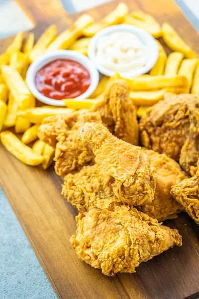 Fried chicken wings with french fries and tomato or ketchup and mayonnaise sauce on wood cutting board - Junk or Unhealthy food style