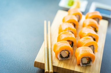 Somon Balık et suşi roll maki wasabi ve soya sosu - Japon yemekleri tarzı ahşap plaka üzerinde