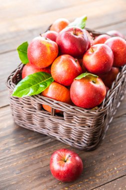 Bir sürü tablo üzerinde kahverengi sepet içinde kırmızı elma meyve