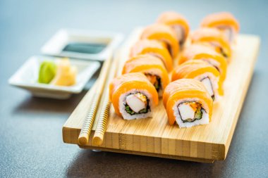 Somon Balık et suşi roll maki wasabi ve soya sosu - Japon yemekleri tarzı ahşap plaka üzerinde